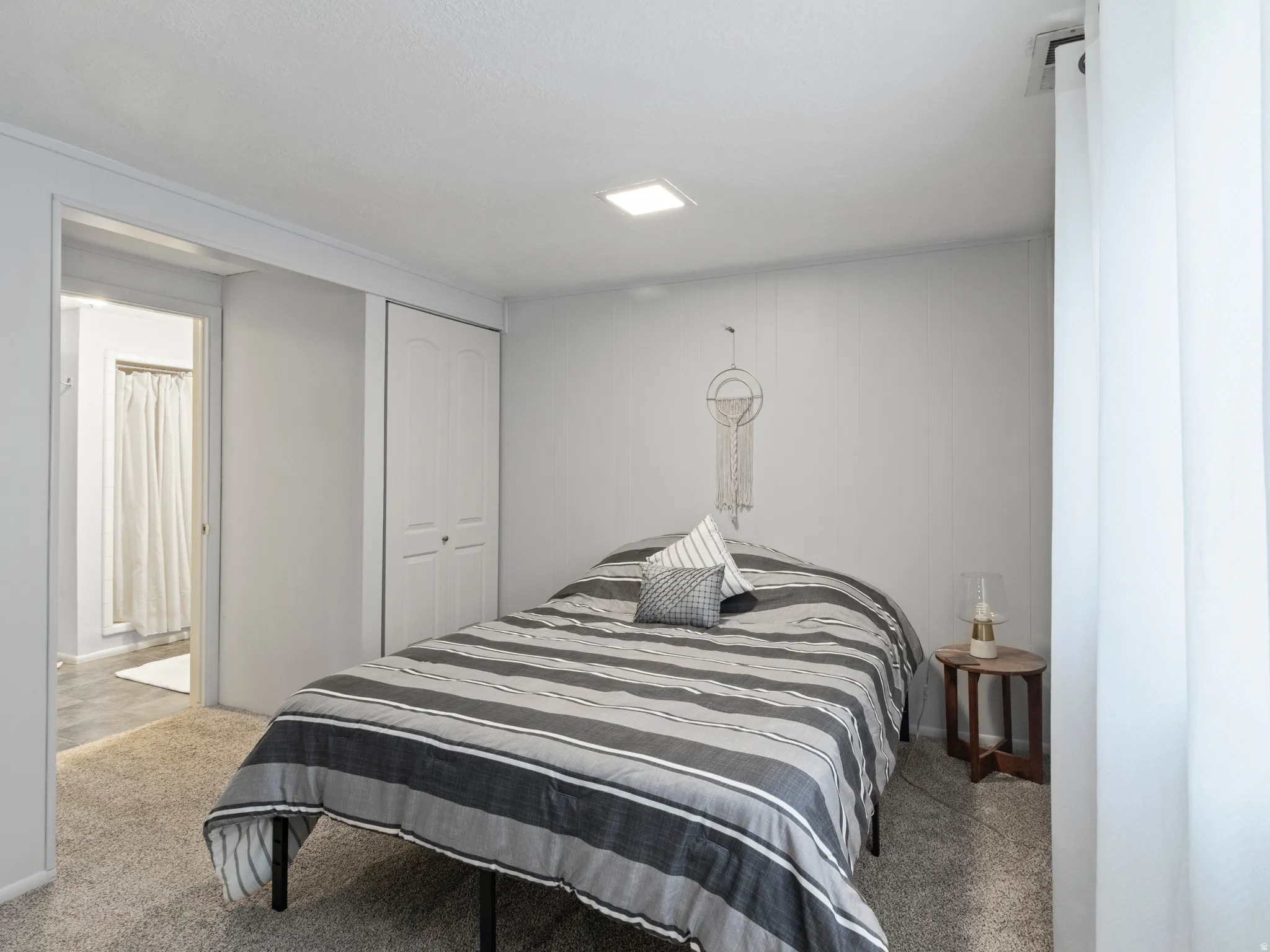 Studio bedroom with carpeted floors. Built-in closet featuring bi-fold doors