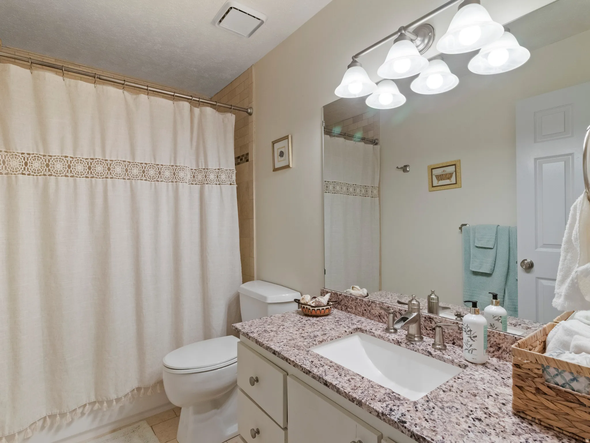 Bathroom vanity featuring a granite countertop, under mount sink, and brushed nickel faucet