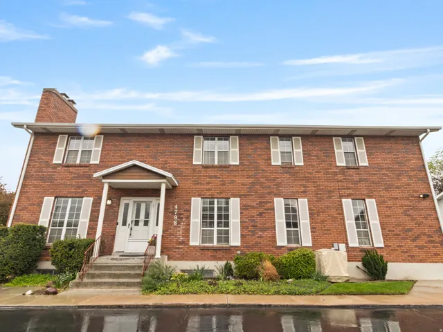 Brick facade with white window shutters and a covered entry