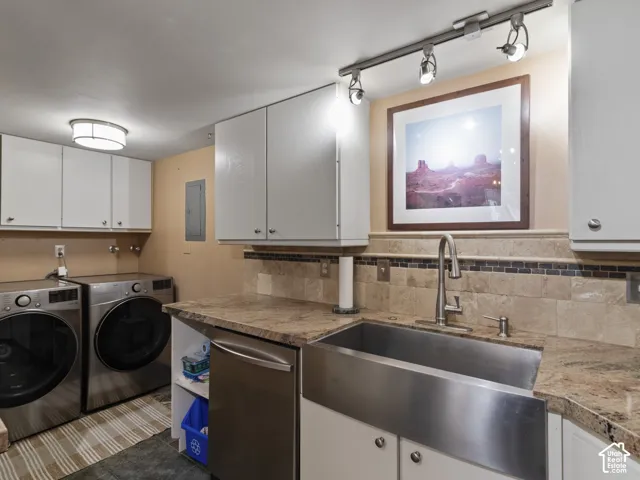 Functional utility space featuring a stainless steel apron front sink, granite countertops, and a tiled backsplash
