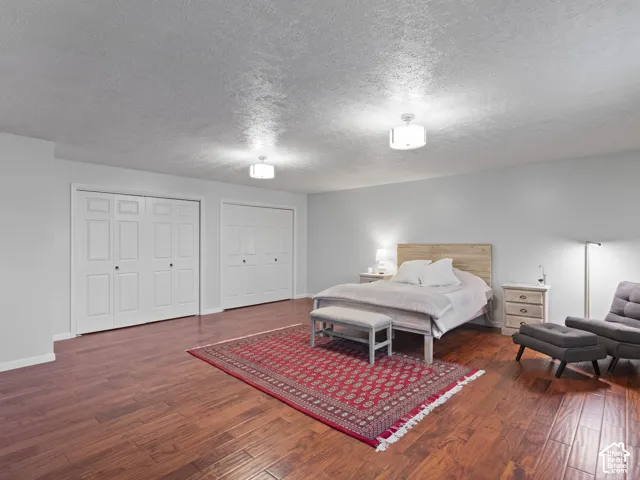 Spacious master bedroom featuring rich wood-finish flooring. Double closets