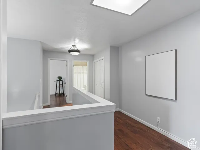 Upper-level hallway featuring wood-finish flooring and light gray walls