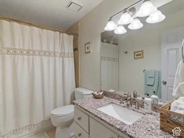 Bathroom vanity featuring a granite countertop, under mount sink, and brushed nickel faucet
