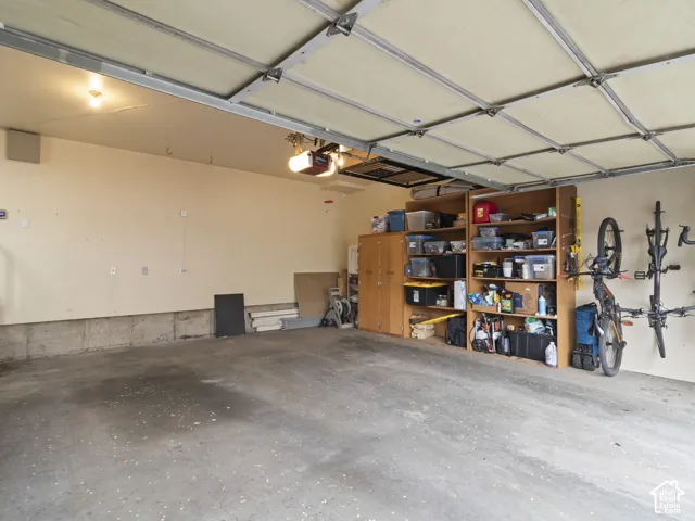 Oversized Spacious garage featuring a concrete floor, overhead garage door with opener, and built-in wood shelving for storage