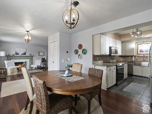Open-concept dining area featuring wood-finish flooring, a contemporary chandelier, and a pass-through opening to the kitchen