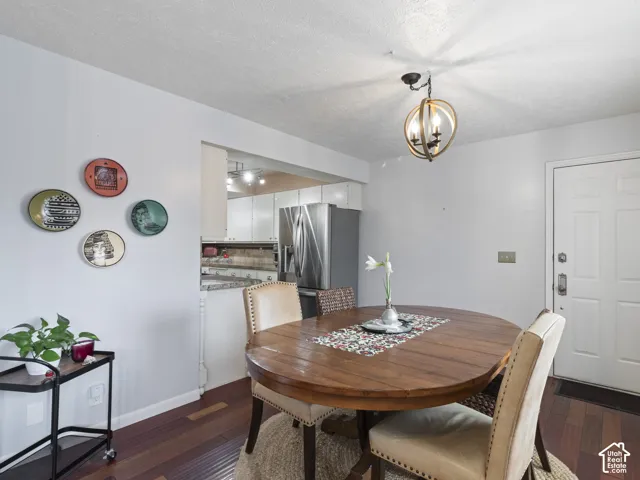 Dining area featuring wood-finish flooring, a contemporary orb chandelier, and an open pass-through to the kitchen