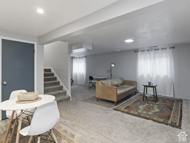 Spacious living area featuring light gray walls, recessed lighting, and a blend of light wood-finish flooring and neutral carpeting