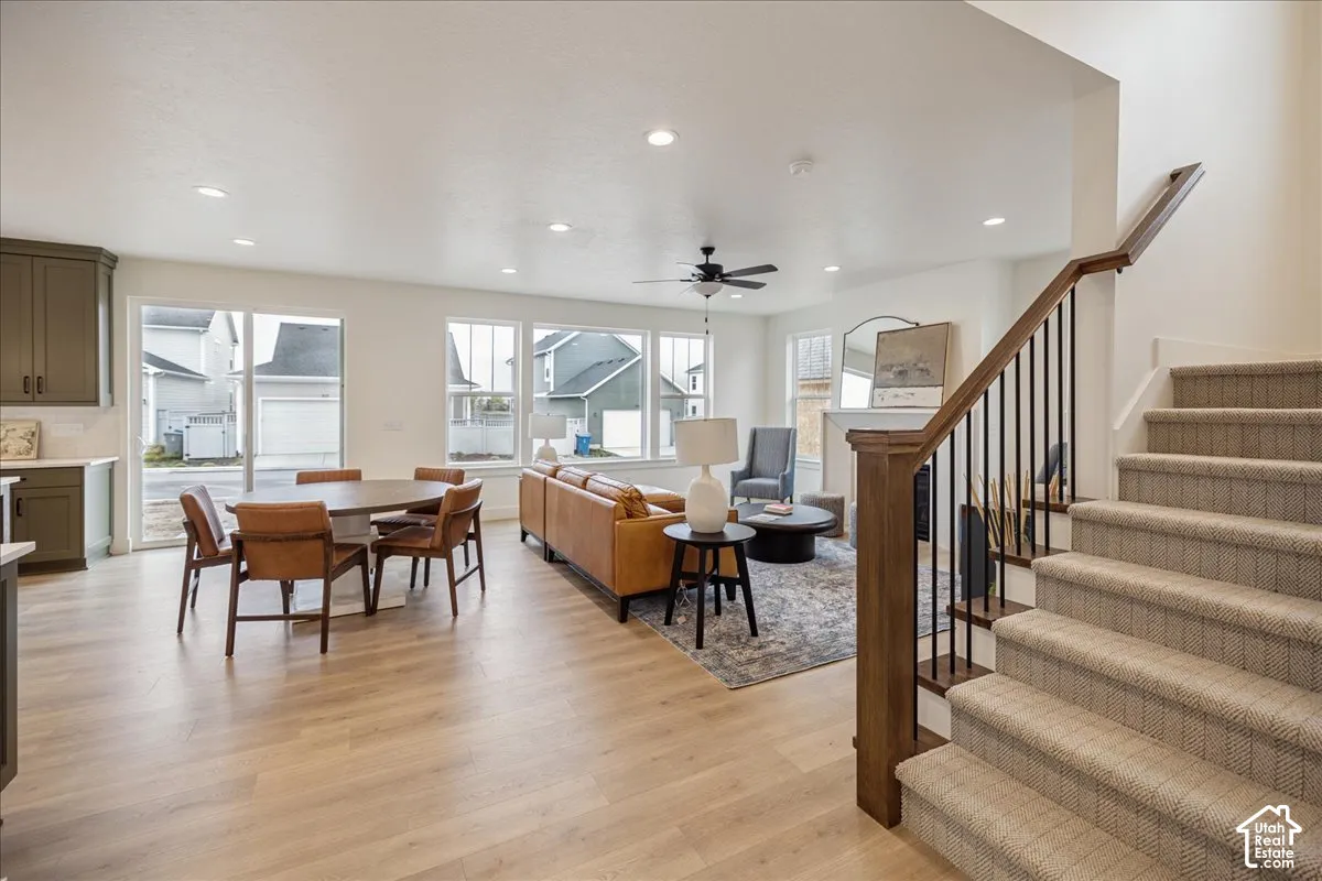 Open-concept interior featuring wood-finish flooring, recessed lighting, a fireplace with a mantel, and a staircase with a wood handrail and metal balusters