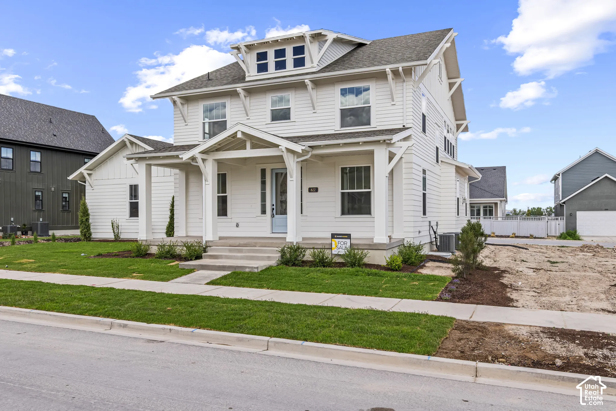 White siding exterior featuring a covered porch with column supports, a light blue front door, multiple windows, and a dormer with additional windows