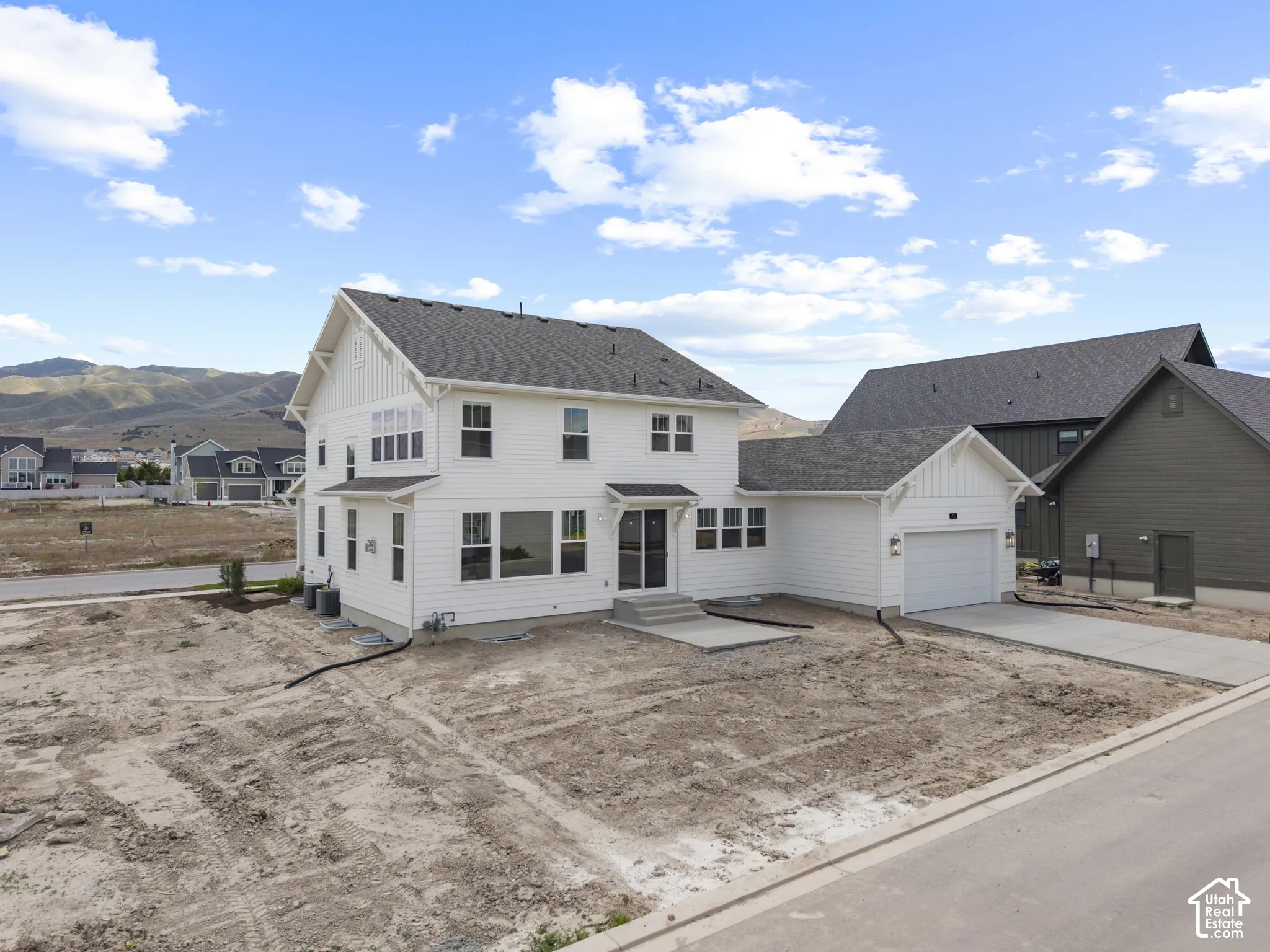 Contemporary two-story residence featuring white horizontal siding, dark shingle roofing, and a prominent front-facing gable