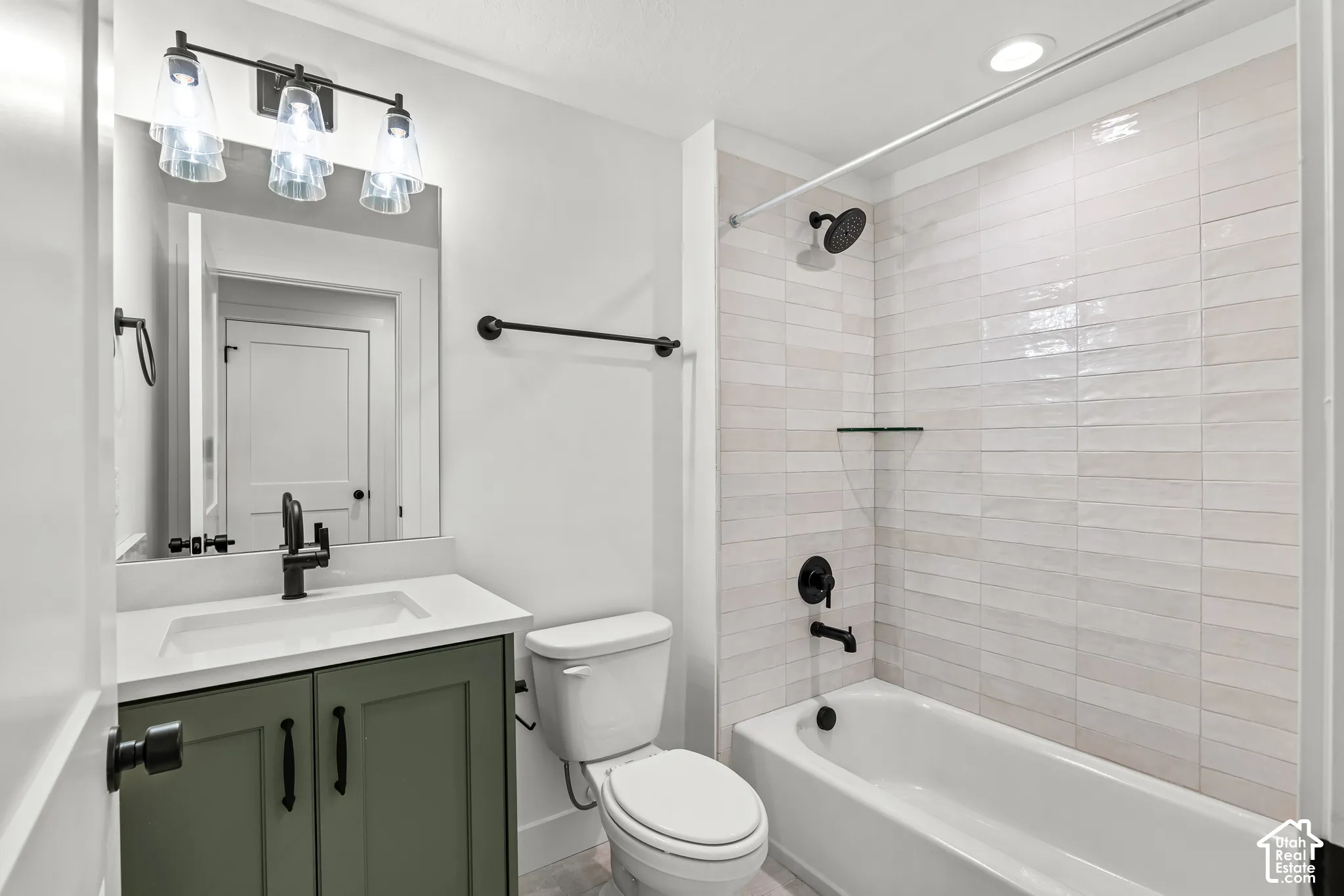 Bathroom featuring a vanity with a green cabinet and a white countertop, a toilet, and a tub with a shower