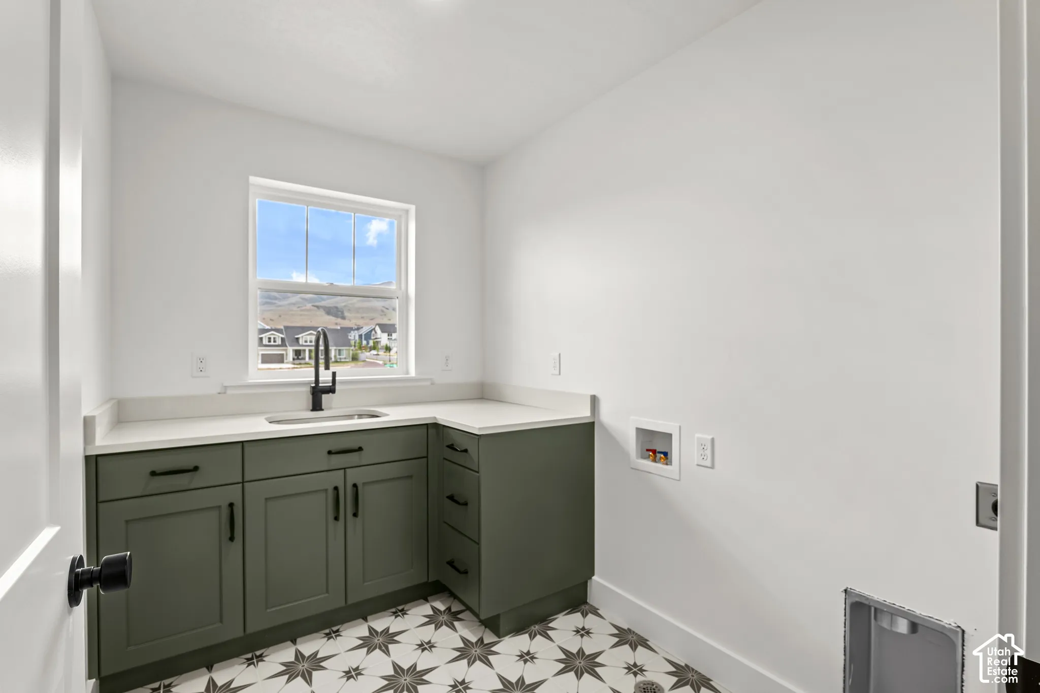 Utility room with patterned tile flooring, olive green cabinetry, and white countertops