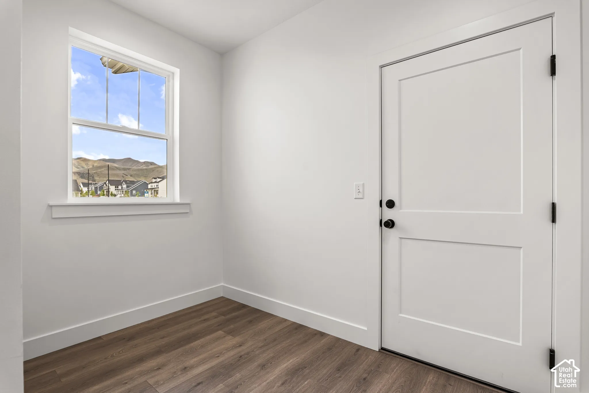 Interior room featuring wood-finish flooring, white walls, and white baseboards