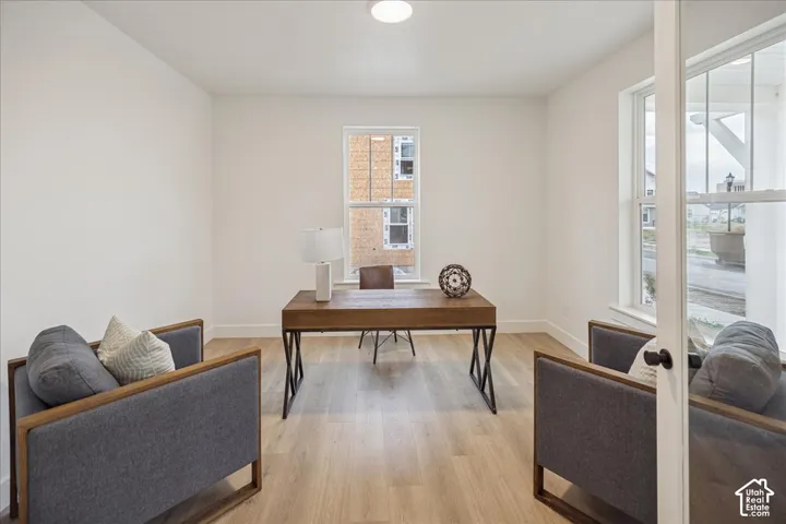 Room with wood-finish flooring, white walls, dual-pane windows, and a French-style glass pane door