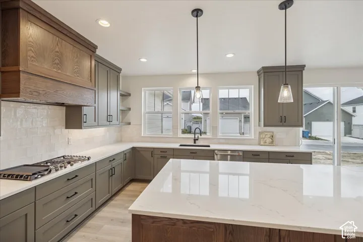 Kitchen featuring a central island with a quartz countertop, custom cabinetry, a wood-finish range hood, tile backsplash, and recessed lighting