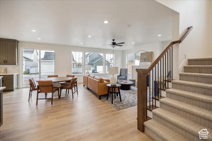 Open-concept interior featuring wood-finish flooring, recessed lighting, a fireplace with a mantel, and a staircase with a wood handrail and metal balusters