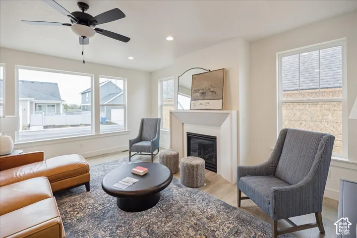 Living area featuring a fireplace with a minimalist surround, wood-finish flooring, recessed lighting, and large windows