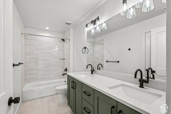 Bathroom featuring a dual vanity with a white countertop and dark green cabinetry