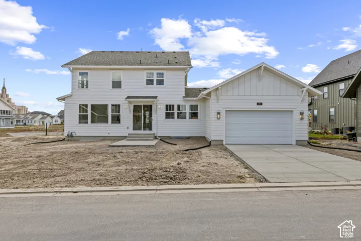 White siding exterior with a two-car garage, concrete driveway, and covered entry
