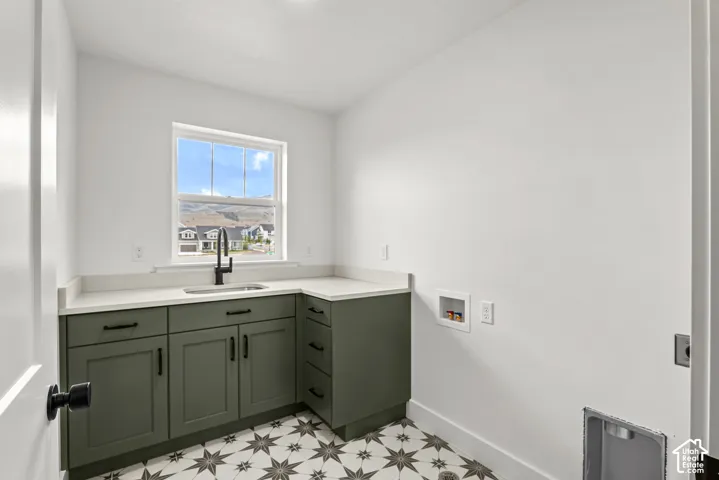 Utility room with patterned tile flooring, olive green cabinetry, and white countertops
