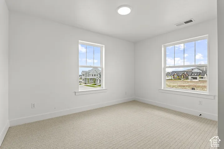 Room featuring light beige carpet flooring, white walls, and bright overhead lighting