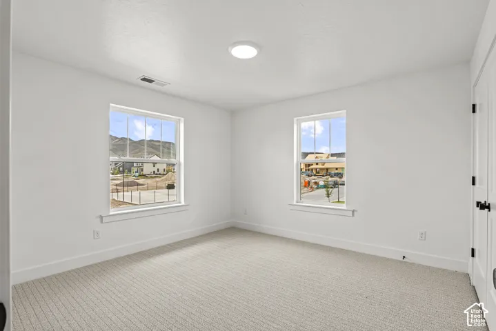 Bright room featuring two windows with mountain scenery, white walls, and neutral-toned carpeting