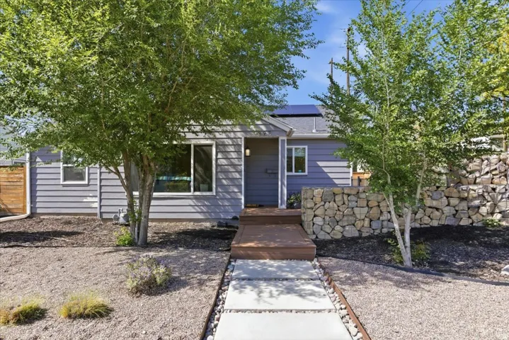 Single-story residence featuring horizontal siding, a covered entry with wood decking, and a low-maintenance gravel front yard