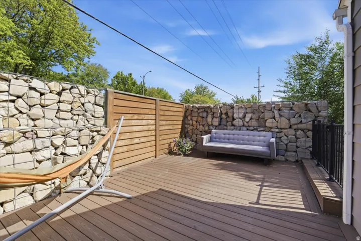 Spacious outdoor deck featuring wood-finish flooring, a gabion wall, and a horizontal slat privacy fence