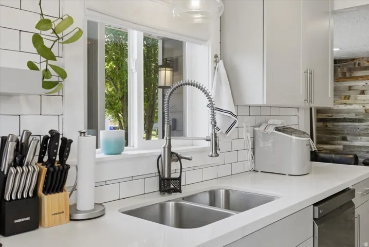 Dual basin stainless steel sink with a high-arc pull-down faucet, framed by white subway tile backsplash and light-toned countertops