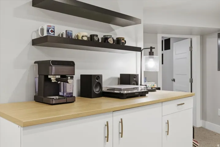 Built-in white cabinetry with a wood-finish countertop, brushed gold hardware, and dark floating shelves