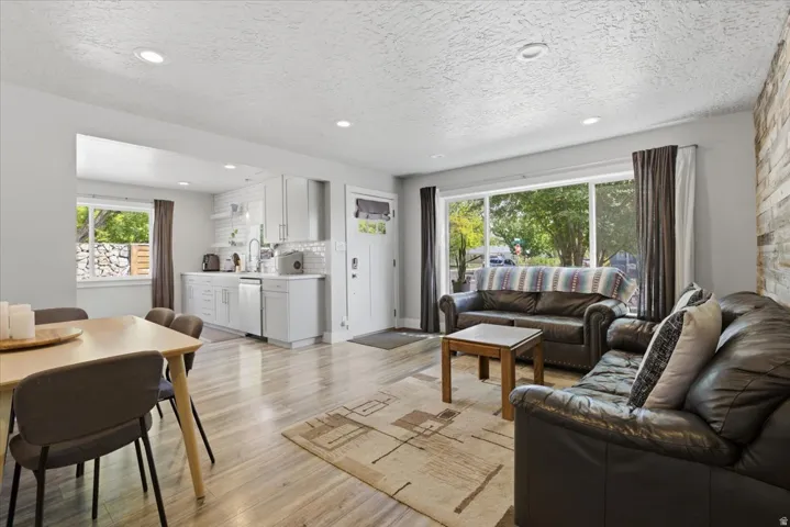 Open-concept living area featuring wood-finish flooring, recessed lighting, and a textured accent wall