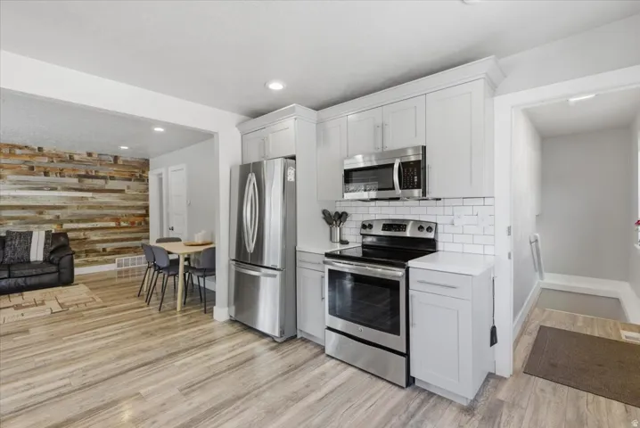 Bright kitchen featuring light cabinetry, stainless steel appliances, and subway tile backsplash