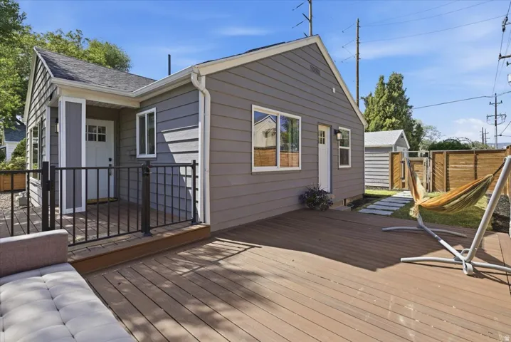 Spacious outdoor deck featuring wood-finish decking, black metal railings, and a stepping stone pathway