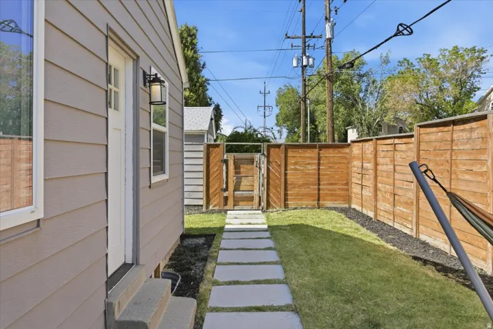 Private side yard featuring a manicured lawn, concrete paver pathway, and wood privacy fencing