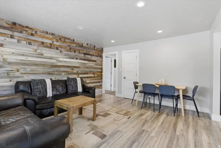Open-concept living space featuring a prominent wood-panel accent wall and wood-finish flooring