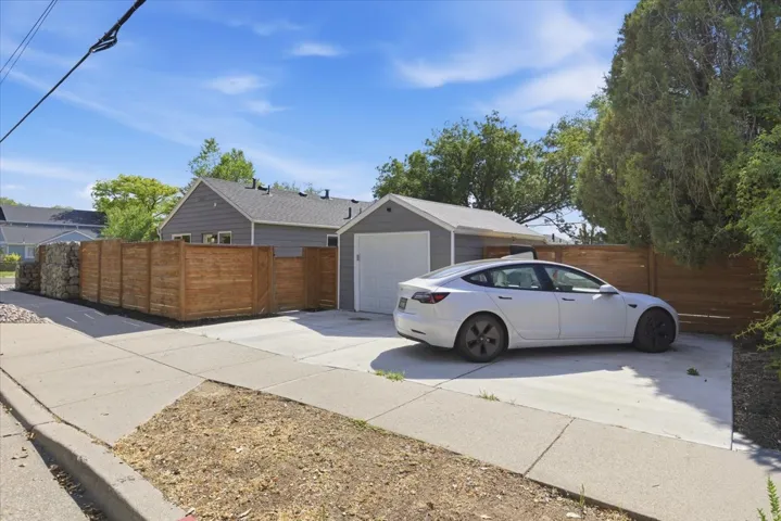 Detached garage with a white overhead door, concrete driveway, and wood privacy fencing