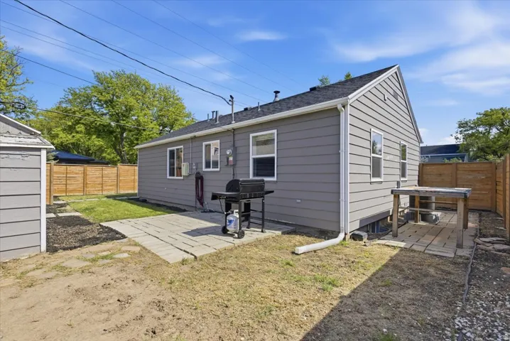 Rear exterior featuring gray horizontal siding, a black shingle roof, and white window trim