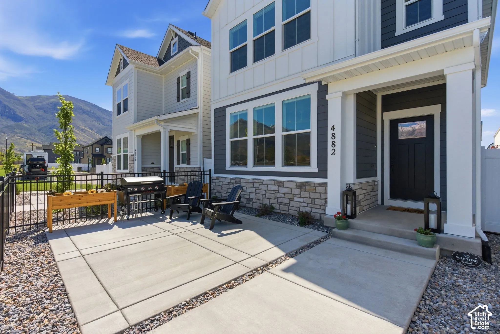 Contemporary exterior featuring charcoal siding, white board and batten accents, and a stone veneer foundation