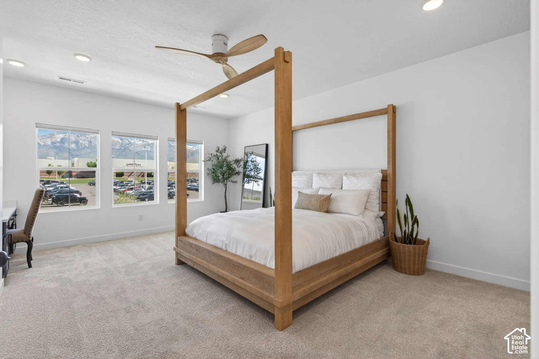 Spacious room featuring three large windows showcasing mountain scenery, light neutral carpet, recessed lighting, and a ceiling fan