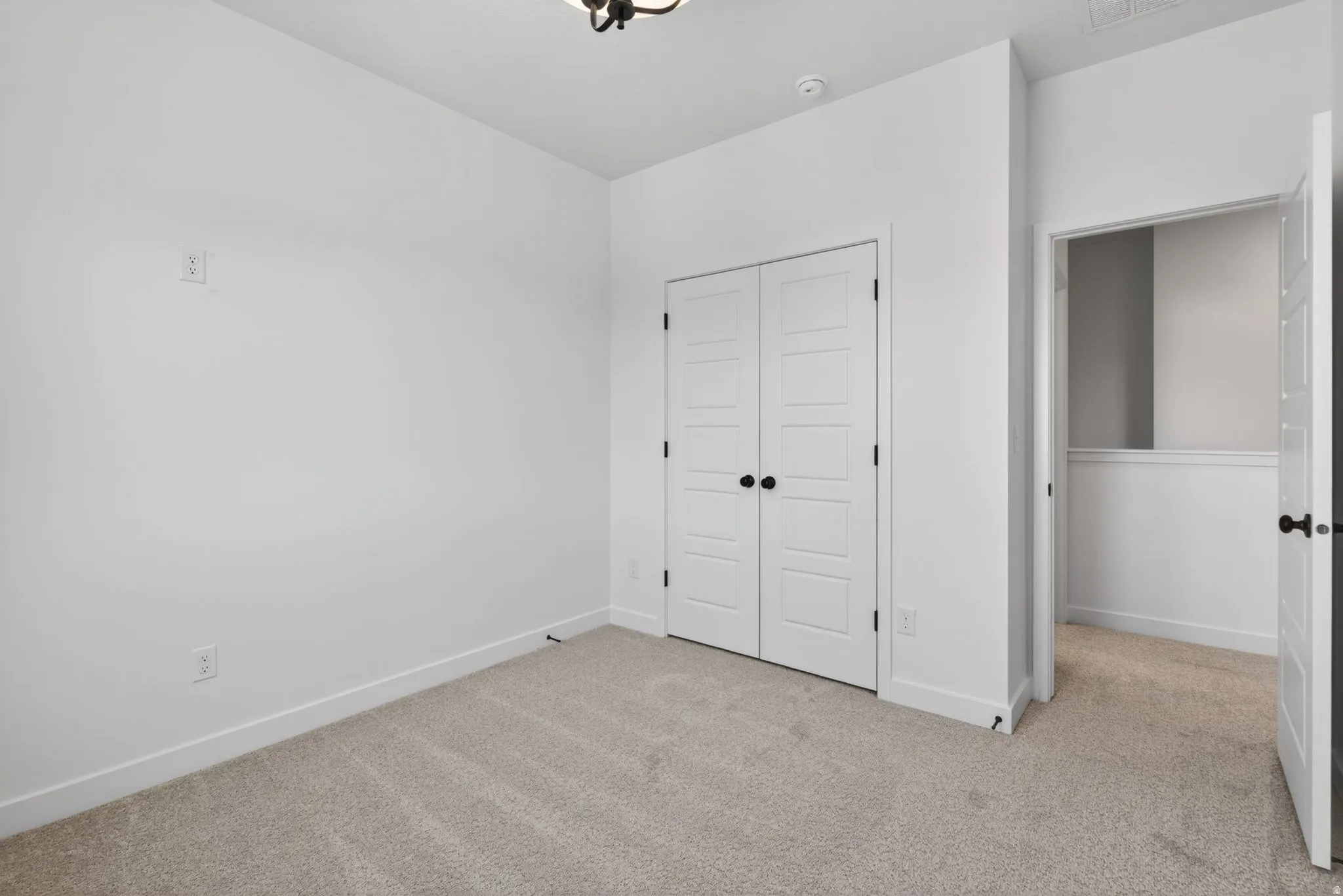 Carpeted room featuring white walls, white trim, and a ceiling-mounted light fixture