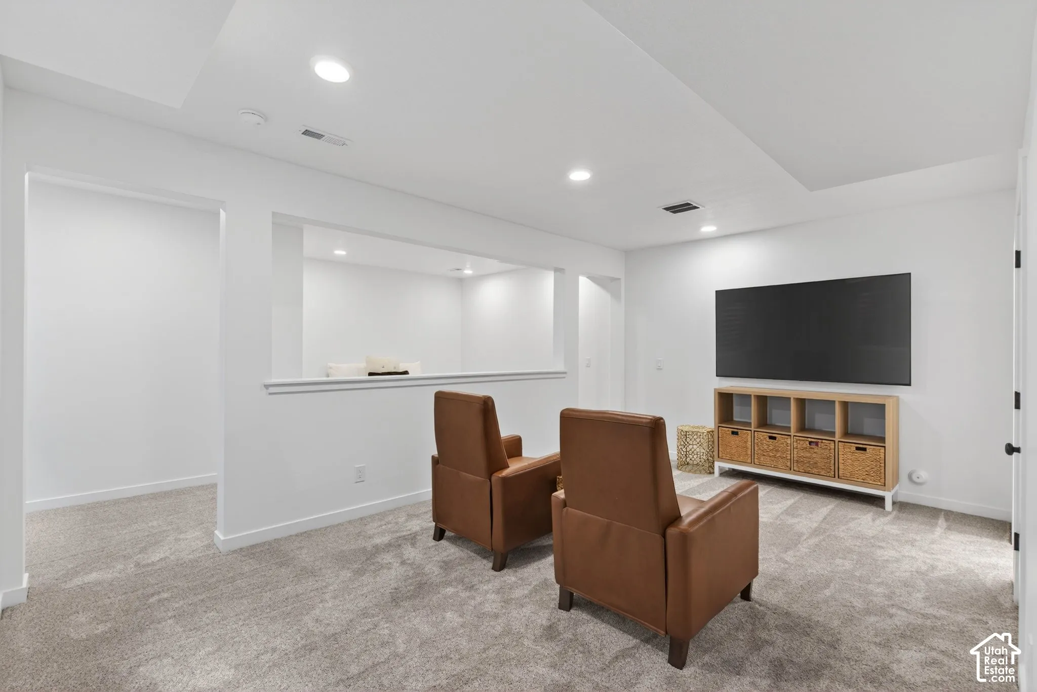 Finished lower-level space featuring recessed lighting, a neutral gray carpet, white walls, and an open wall architectural detail