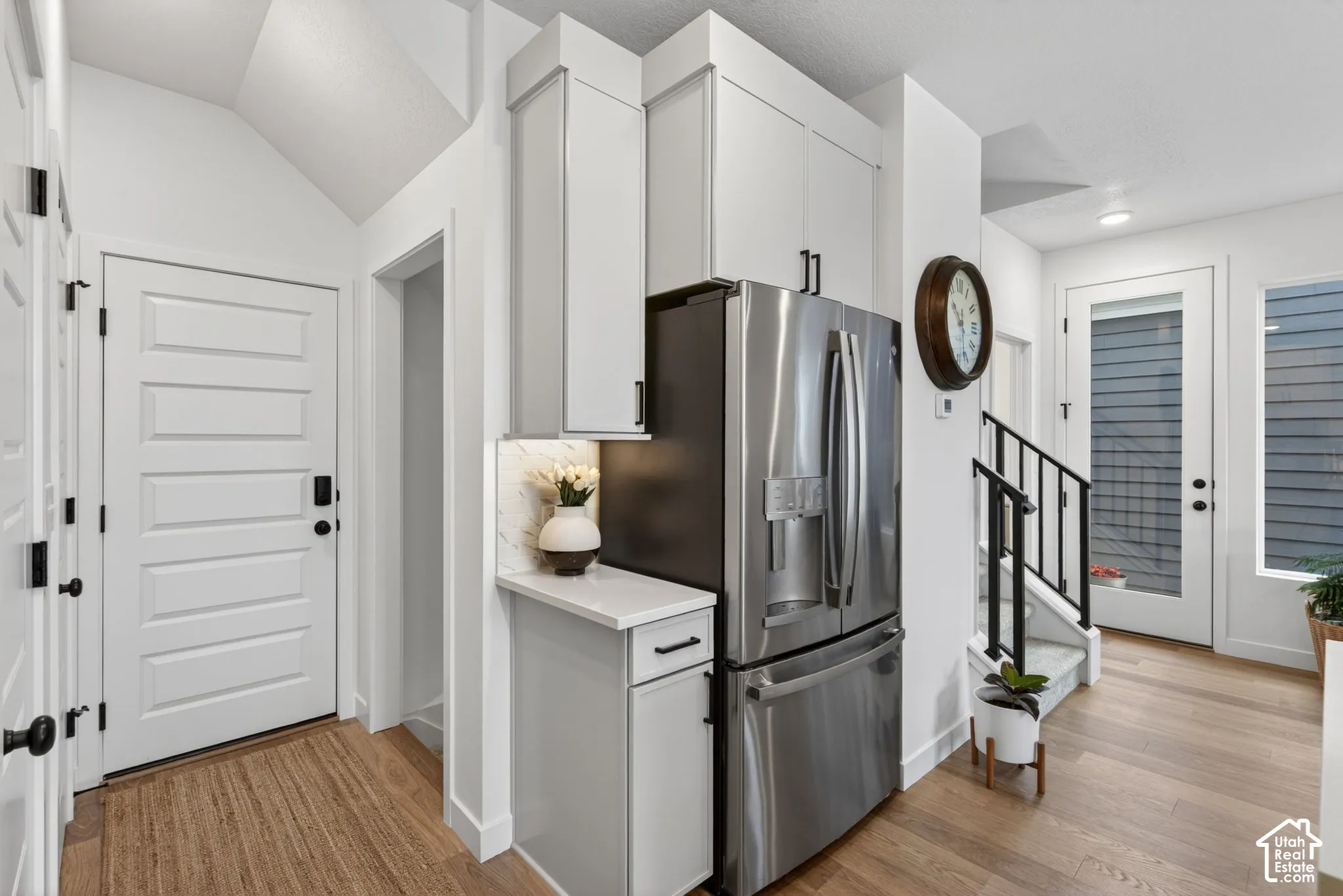 Contemporary kitchen cabinetry with integrated stainless steel refrigerator, white quartz-finish countertop, and under-cabinet lighting