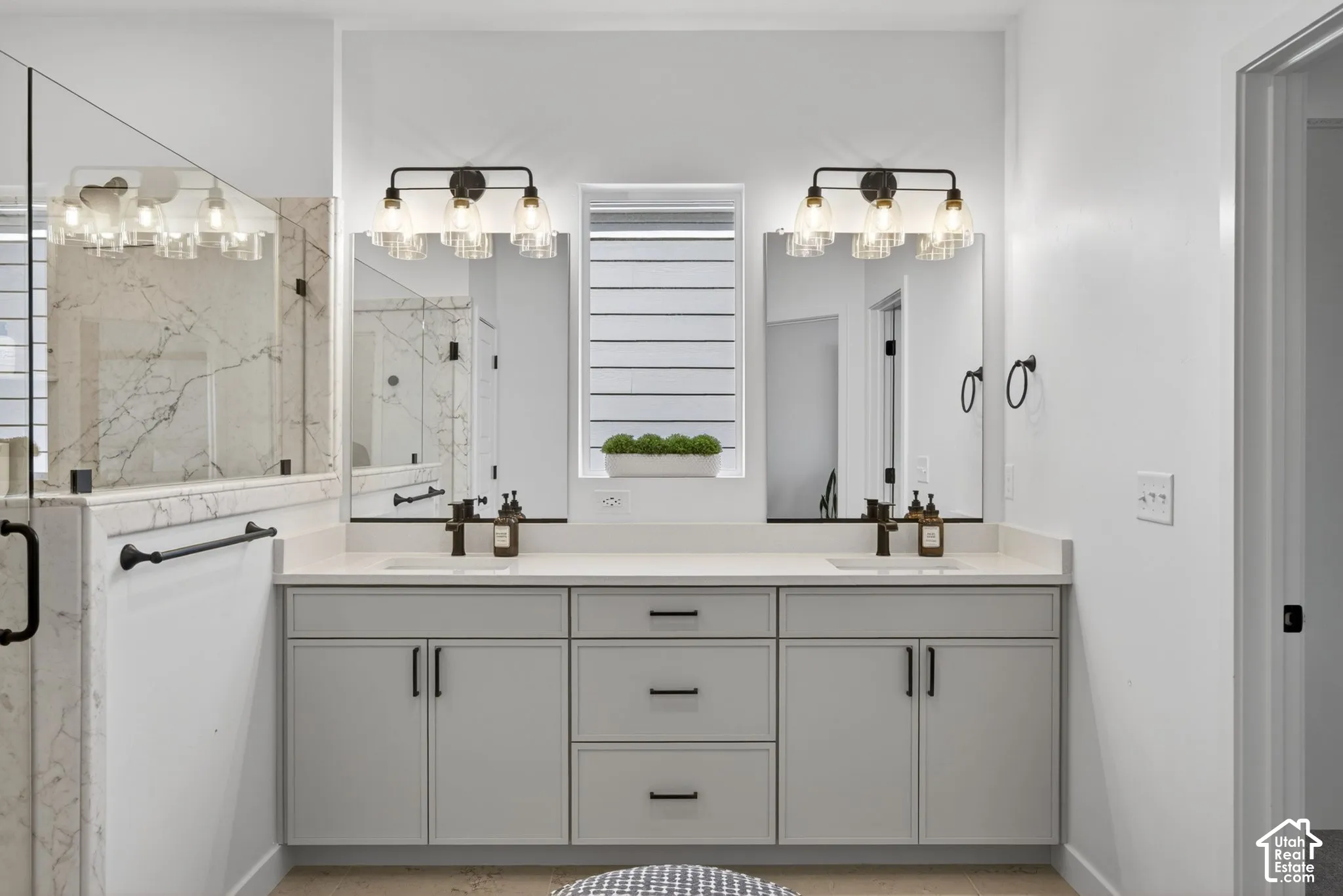 Double vanity featuring light gray cabinetry, integrated sinks with matte black faucets, and light-toned countertops