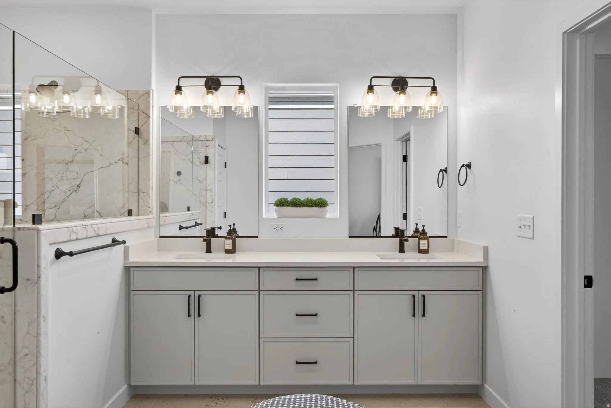Double vanity featuring light gray cabinetry, integrated sinks with matte black faucets, and light-toned countertops