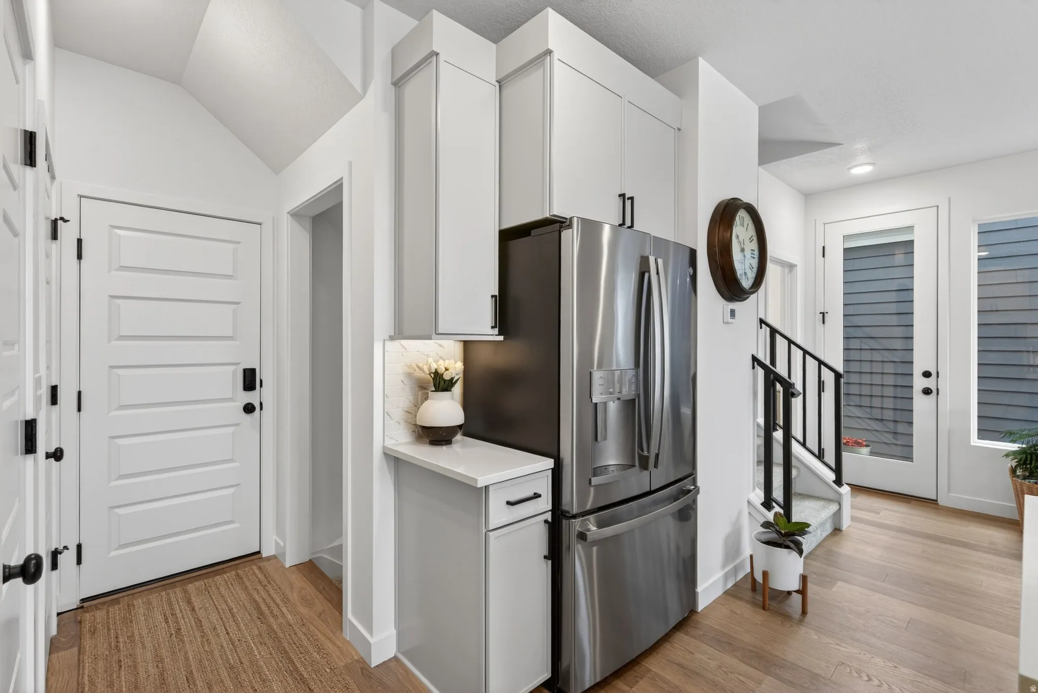 Contemporary kitchen cabinetry with integrated stainless steel refrigerator, white quartz-finish countertop, and under-cabinet lighting