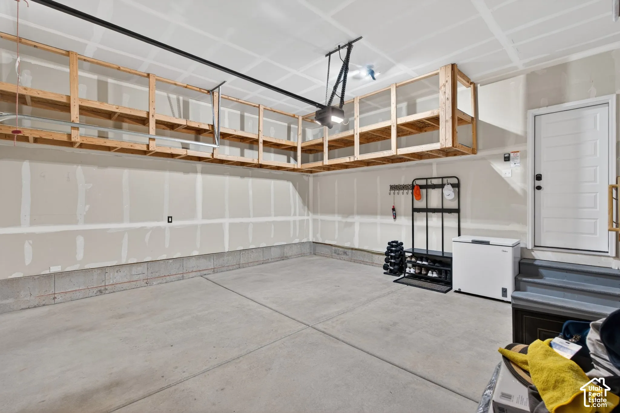 Spacious garage featuring a concrete floor, built-in overhead storage shelving, and an automatic garage door opener