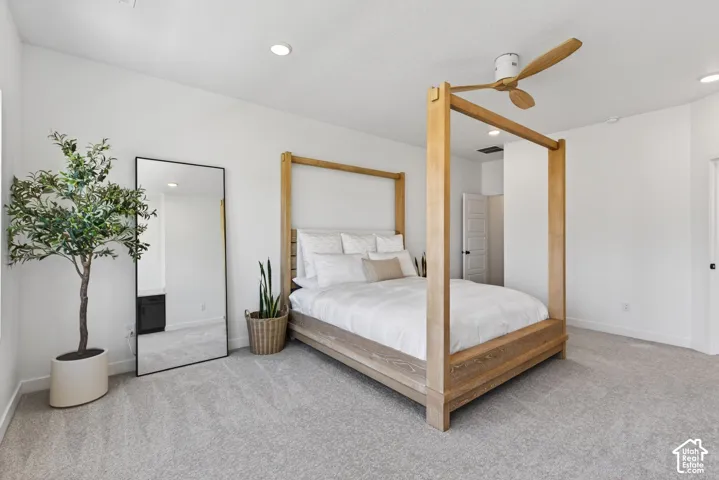 Spacious carpeted room featuring a ceiling fan with wood-finish blades, recessed lighting, and white walls