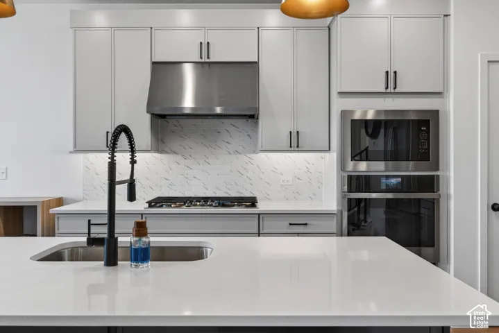 Modern kitchen featuring light gray cabinetry, stainless steel appliances, and a gas cooktop