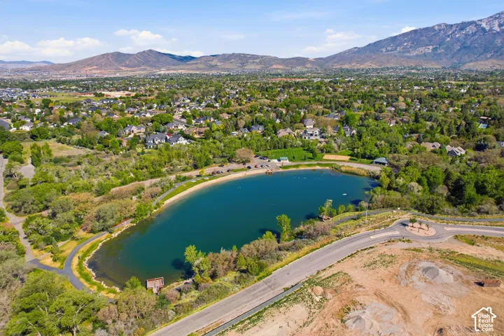 Expansive water feature with surrounding green spaces, paved pathways, and a sandy shoreline