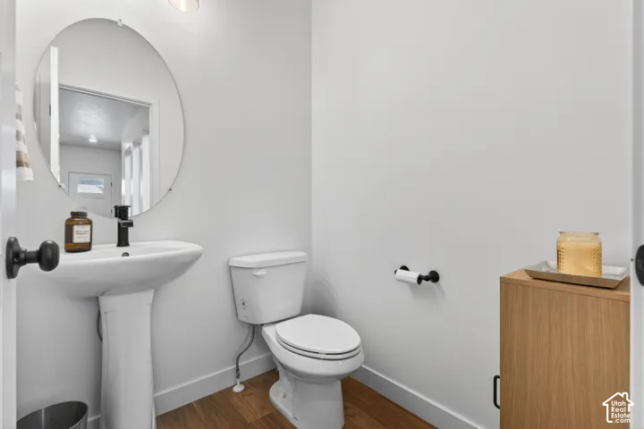 Pedestal sink with a matte black faucet, complemented by a circular wall-mounted mirror